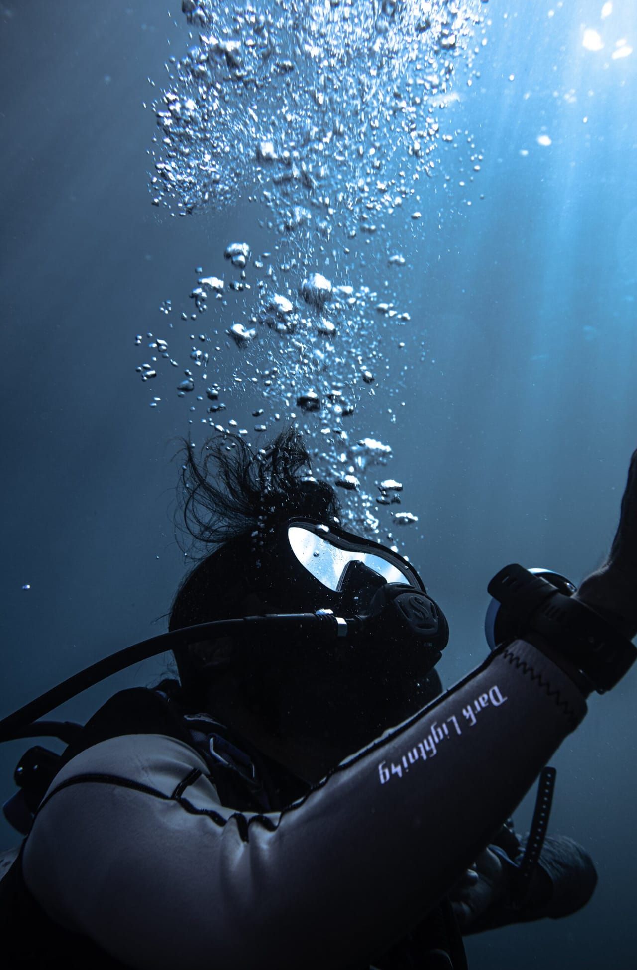 A diver's silhouette against the surface, trailing bubbles